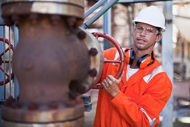 Worker adjusting gauge at oil refinery  air valve stock pictures, royalty-free photos & images
