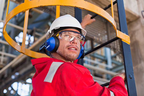 travailleur escalade échelle de raffinerie de pétrole - lunettes de protection photos et images de collection