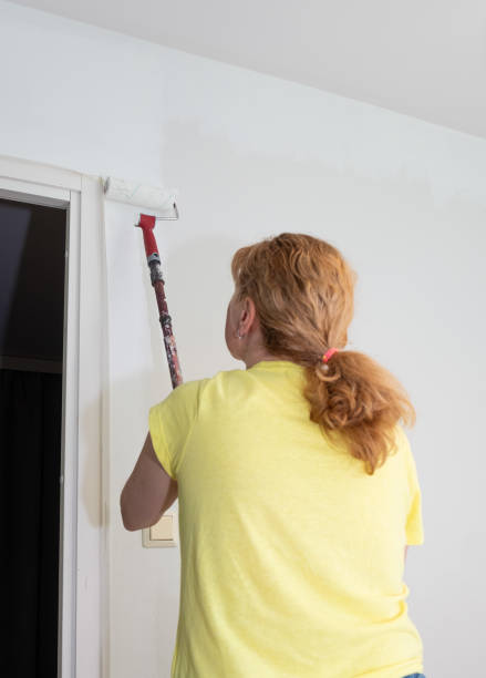 istock A Caucasian woman paints a wall in a room with a paint roller. 1493203036