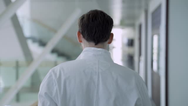 Young scientist or med student puts on a lab coat in a futuristic looking lab