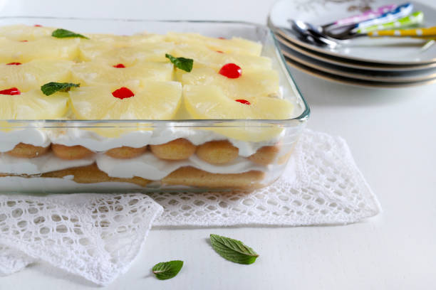 Homemade pineapple tiramisu isolated on white background. Mint leaves decoration and candied cherries. Copy space.