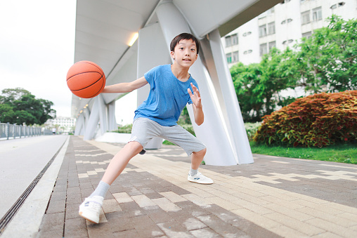 Portrait of a boy kid playing with a basketball in park