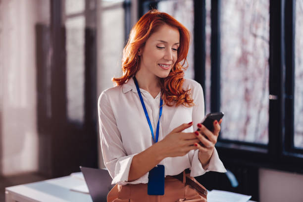 istock Beautiful young businesswoman using mobile phone in office while leaning on desk. 1493207814