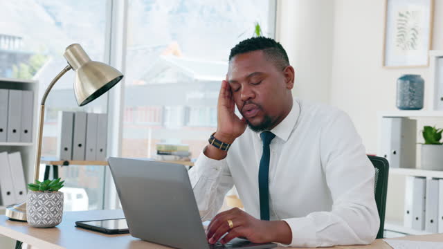 Corporate black man, headache and laptop at office desk with burnout, depressed or overworked. African businessman, exhausted and mental health for stress, fatigue and frustrated at workplace table
