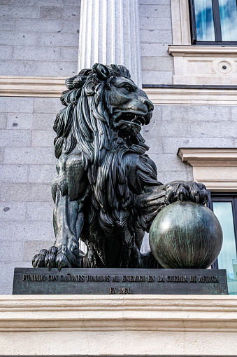 Madrid, Spain. April 15, 2023. Vertical image of one of the bronze lions that protect the entrance of the congress of spain, in madrid, cast with cannons of the war of africa.