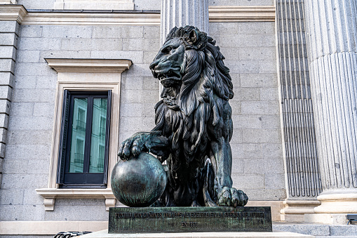 Madrid, Spain. April 15, 2023. Horizontal image of one of the bronze lions that protect the entrance of the congress of spain, in madrid, cast with cannons of the war of africa.