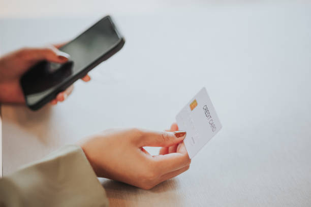 istock online payment Young woman's hand holding a credit card and using a smartphone for online shopping 1493213211