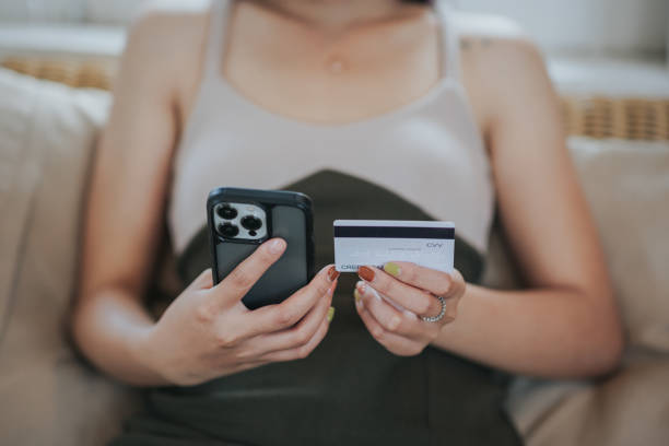 istock online payment Young woman's hand holding a credit card and using a smartphone for online shopping 1493213213