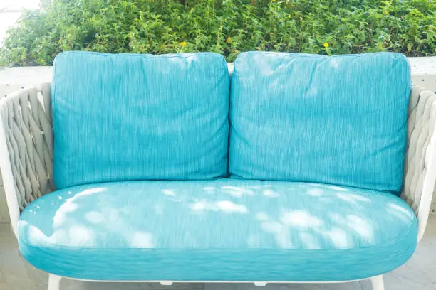Sea-blue sofa rattan chairs set outside against at sidewalk swimming pool. Relaxing chairs