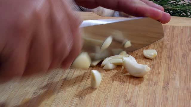 Chopping garlic with knife on cutting board