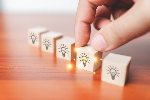 istock Male hand holds wooden cube with light bulbs icon , Idea and creativity concept , Teamwork brainstorming ideas, evaluation and selection for business development. 1493229219