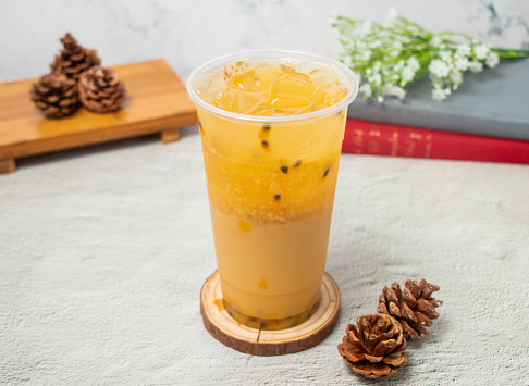 Passion fruit iced tea served in disposable glass isolated on background top view of taiwan drink
