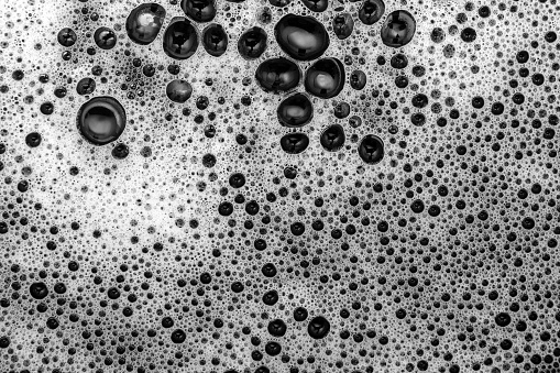 Goiânia, Goias, Brazil – May 22, 2023: Detail of white foam texture on a black surface. Black and white image.