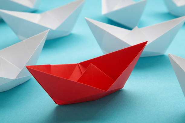 istock Leadership concept. Red leader paper ship leading among white on blue background. 1493241872