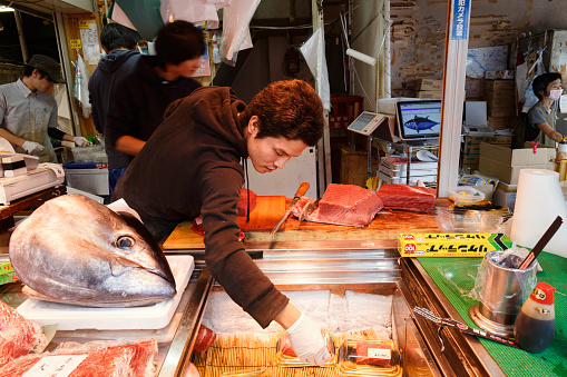 Tokyo, Japan - May 21, 2022 : fresh meat and head of tuna fish slice and cook for sushi and shasemi menu in seafood stall at street food in Tsukiji Fish Market, Tokyo, Japan.
