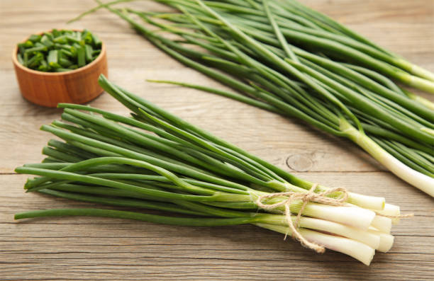 istock Fresh green onions on a cutting board on grey wooden background. 1493246498