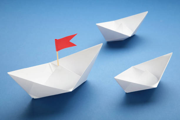 istock White paper ship and red flag on blue background. 1493247081