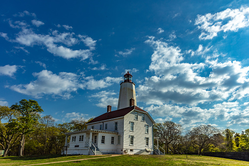 Perched on the picturesque Sandy Hook peninsula in New Jersey, the oldest working lighthouse stood tall, its majestic presence accentuated against a vibrant sky, casting its guiding light over the endless horizon of the Atlantic Ocean.