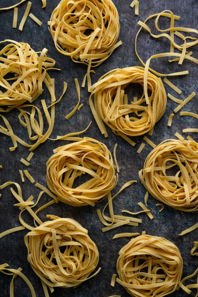 istock Tagliatelle Pasta Nests Surrounded by Scattered Broken Noodles 1493256377