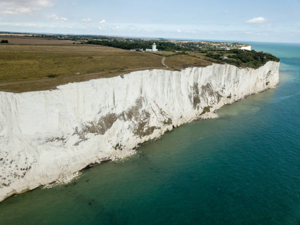 Aerial view of The White Cliffs of Dover.The White Cliffs of Dover is the region of English coastline facing the Strait of Dover and France. The cliff face, which reaches a height of 350 feet (110 m), owes its striking appearance to its composition of chalk accented by streaks of black flint, deposited during the Late Cretaceous. The cliffs, on both sides of the town of Dover in Kent, stretch for eight miles (13 km). The White Cliffs of Dover form part of the North Downs. A section of coastline encompassing the cliffs was purchased by the National Trust in 2016.