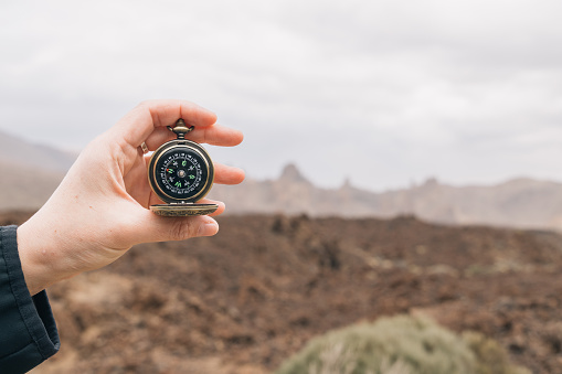 Hand holding a compass, scouting equipment, travel concept