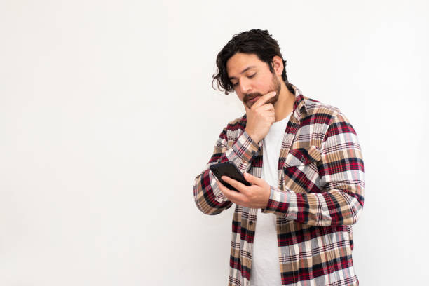 istock Hispanic-Arabian man looking his cell phone with pensative face and copy space 1493269528