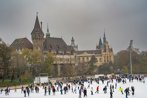 Budapest, Hungary - November 27th, 2022: Ice skaters near the Vajdahunyad castle in the Budapest city park, on an overcast winter day.