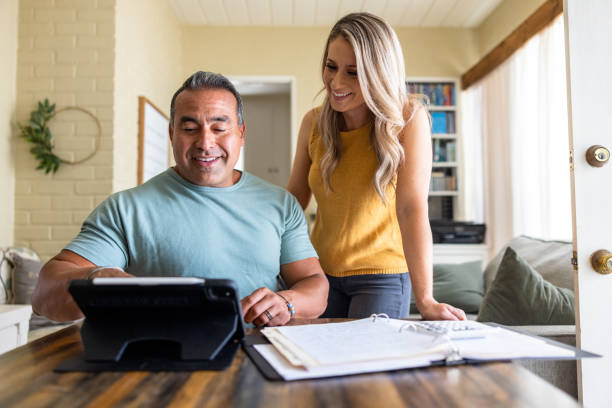 Diverse married couple at home working on their home finances stock photo