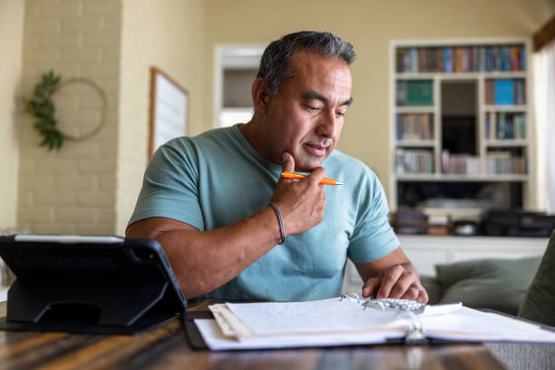 uomo maturo che lavora da casa usando un computer - 1u foto e immagini stock