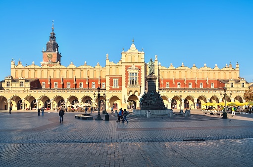 Krakow, Poland - October 21, 2012: The statue of Adam Mickiewicz and Cloth Hall (Sukiennice) on the main square in Krakow. Old Town in Krakow (Poland) is listed by UNESCO organisation.
