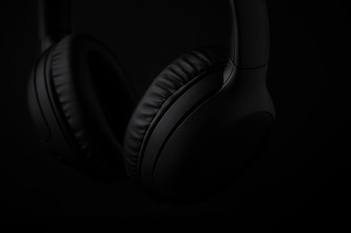 Close up photo in low key lighting of black headphones on a black background.