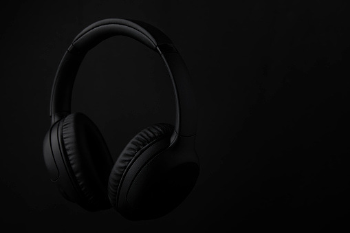 Still life of black headphones floating in the air on a dark background