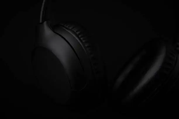 Close up photo in low key lighting of black headphones on a black background.