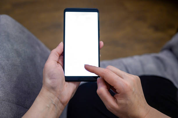 istock a person sitting on a couch and holding a smart phone with a white screen 1493283056