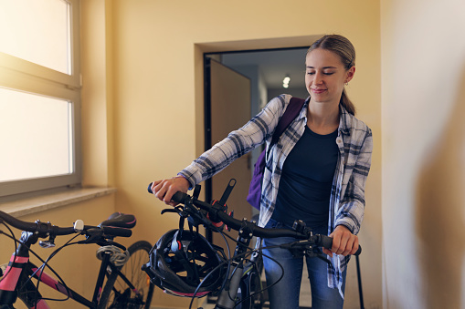Teenage girl going out to ride bike. She is wheeling her bike through the door to the corridor and to the elevator.
Canon R5