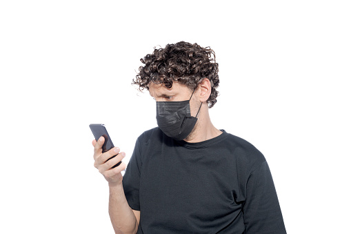 Middle-aged man in a black cover-up looking at his smartphone, on a white background.