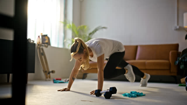 SLOW MOTION Fit young woman doing mountain climber exercises on living room floor by dumbbells at home. Healthy lifestyle,exercise,fitness,active lifestyle. Shot in 8K Resolution.