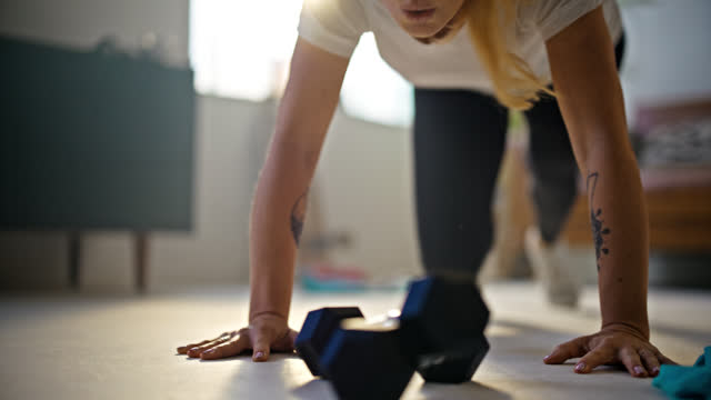 SLO MO Determined,fit young woman with tattoos doing mountain climber exercises on floor in sunny living room at home. Healthy lifestyle,fitness,active lifestyle,self improvement,strength,dedication. Shot in 8K Resolution.