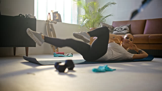 SLOW MOTION Fit young woman doing bicycle crunch sit-ups on exercise mat,doing home workout on floor in living room. Healthy lifestyle,active lifestyle,strength,vitality,exercise and fitness. Shot in 8K Resolution.