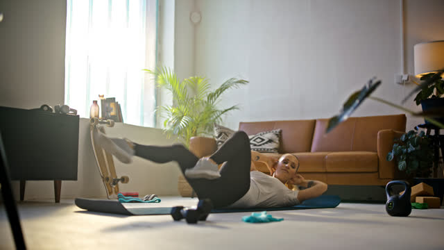 SLO MO Fit young woman doing bicycle crunch sit-ups on exercise mat,doing home workout on floor in sunny living room. Healthy lifestyle,active lifestyle,strength,vitality,exercise and fitness. Shot in 8K Resolution.