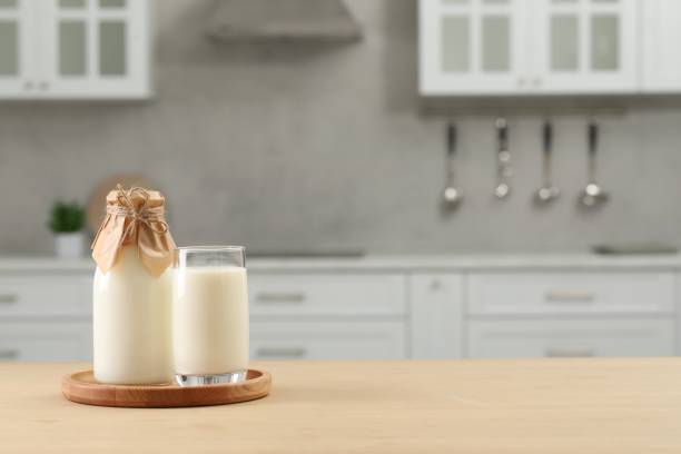 istock Bottle and glass with milk on wooden table in kitchen, space for text 1493296903