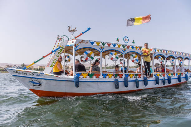 Nile River, Luxor, Egypt - April 13,2023 A traditional boat sails the Nile River in Egypt, adorned with colorful decorations and a national flag, showcasing cultural and maritime heritage on a sunny day.
