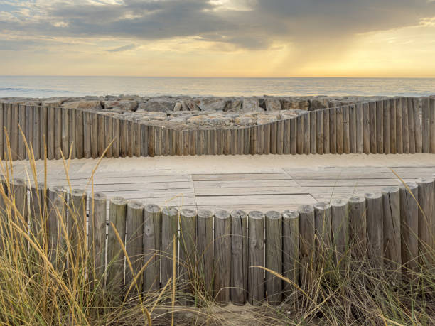 drewniane chodniki dla pieszych, zbudowane nad wydmą, która służy do zapewnienia dostępu do plaży w plaży furadouro, świeci o zachodzie słońca. ovar, aveiro, portugalia, europa - beach boardwalk grass marram grass zdjęcia i obrazy z banku zdjęć