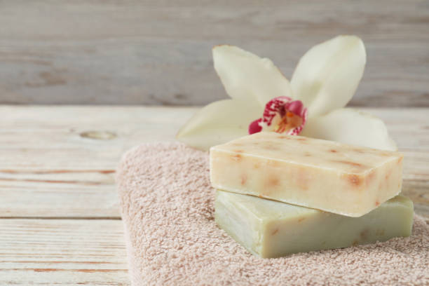 istock Soap bars, terry towel and lily on wooden table, closeup. Space for text 1493304928