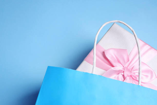 istock Bright paper shopping bag with gift box on light blue background, top view. Space for text 1493305026