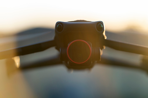 Drone aircraft with blurred fast rotating propellers and video camera flying in air.