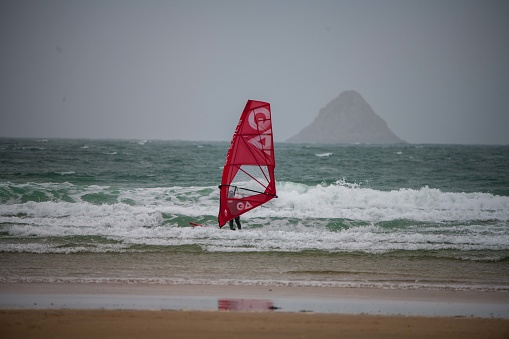 Crozon, France - April 10, 2023: Red Windsurf in Crozon with the Pointe de Pen-Hir