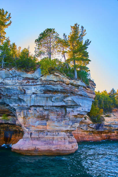 istock Sapphire lake water with red and white pictured rocks cliff and sunset through trees 1493310465