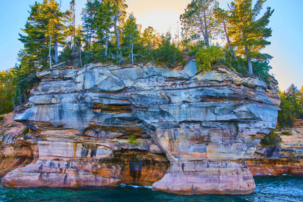 istock Sun shining through forest above pictured rocks cliff face with sapphire blue lake water 1493311059