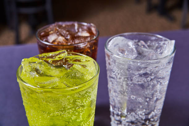 three coke or pepsi soft drinks dark brown, lime green, clear bubbly soda beverages - lime imagens e fotografias de stock